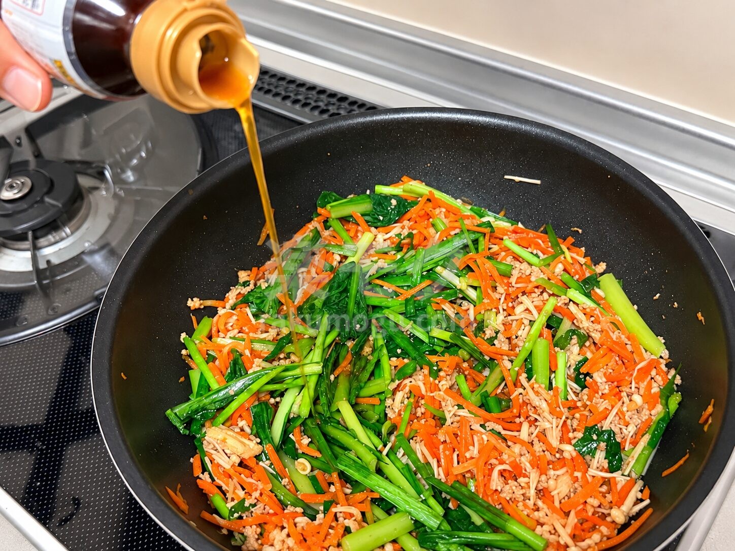 フライパンの具材にごま油を回しかける
